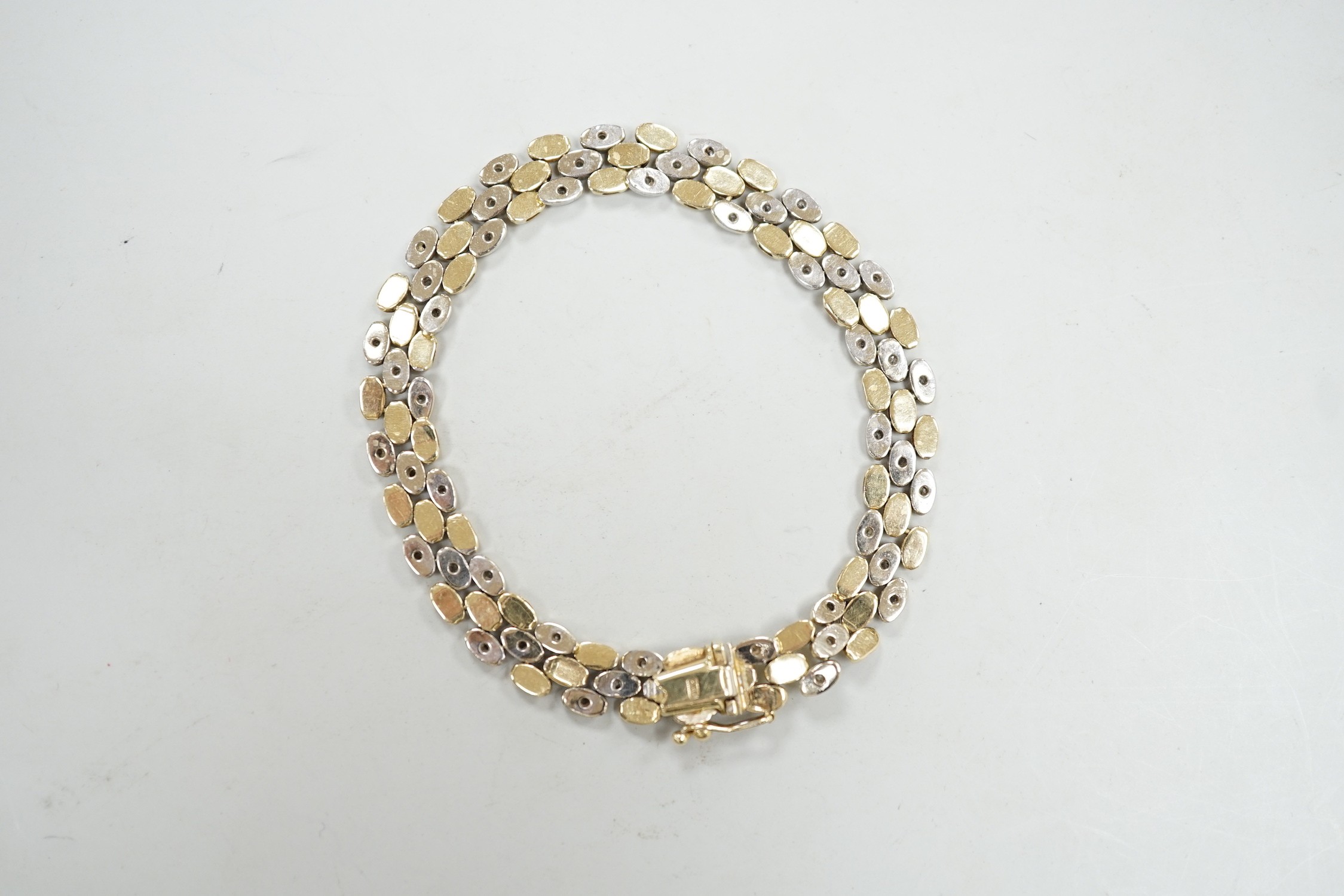 A modern two colour 585 and diamond chip set bracelet, 18cm, gross weight 17.3 grams.